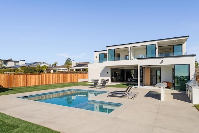 rear view of house featuring a fenced in pool, a patio area, a balcony, and a lawn