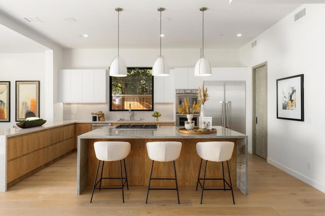 kitchen with white cabinetry, stainless steel appliances, and hanging light fixtures