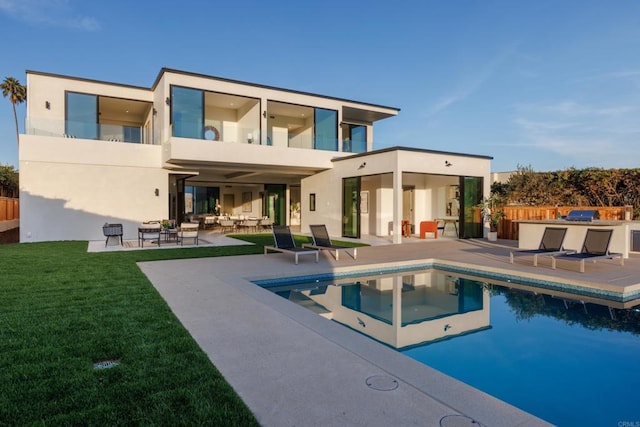 rear view of house featuring a balcony, a yard, a fenced in pool, and a patio