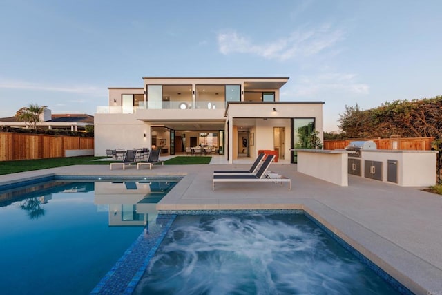 back of house featuring area for grilling, a fenced in pool, a balcony, and a patio area