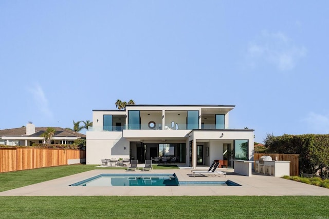 rear view of house featuring a patio, a balcony, a lawn, an outdoor kitchen, and a fenced in pool