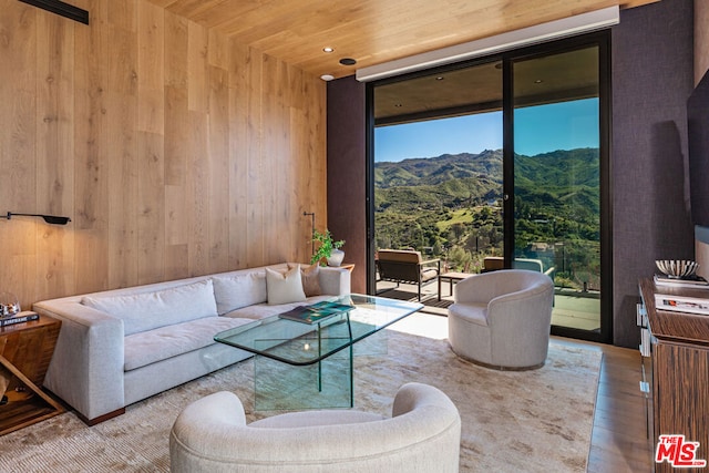 living room featuring wood ceiling, a mountain view, hardwood / wood-style flooring, and wooden walls