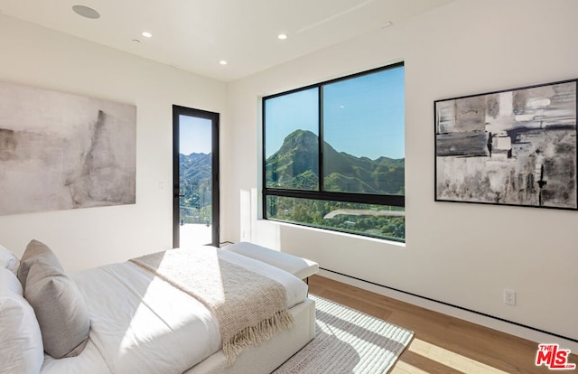 bedroom with a mountain view and light hardwood / wood-style flooring