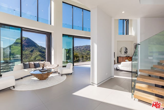 tiled living room with a wealth of natural light, a mountain view, and a towering ceiling