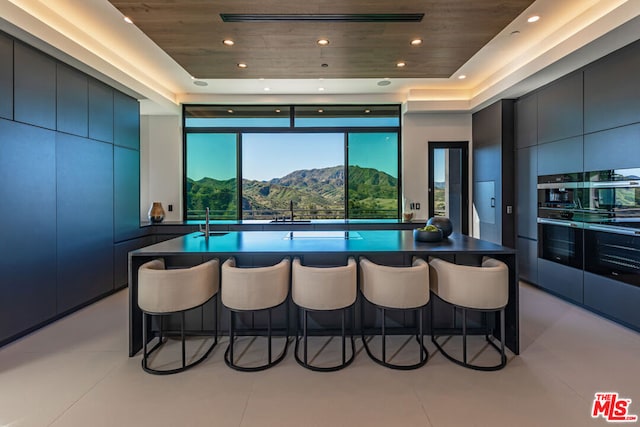 kitchen with a mountain view, wooden ceiling, and a kitchen breakfast bar