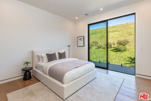 bedroom with hardwood / wood-style floors and access to outside