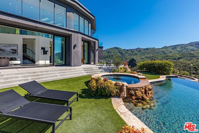 view of swimming pool with an in ground hot tub and a mountain view