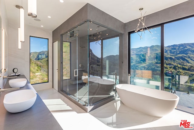 bathroom with a healthy amount of sunlight, a mountain view, separate shower and tub, and vanity