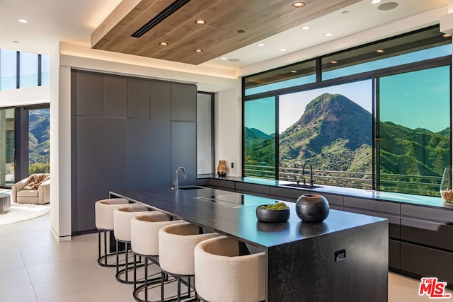 kitchen with a spacious island, wood ceiling, a kitchen breakfast bar, sink, and a mountain view