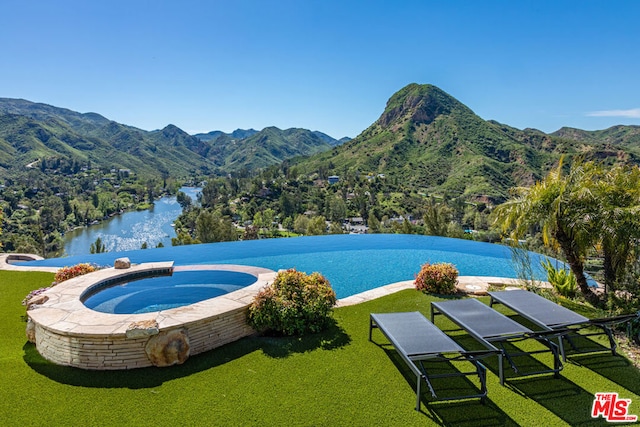 view of pool with a water and mountain view and a yard