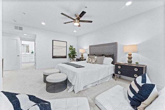 bedroom featuring ceiling fan, light colored carpet, and ensuite bath