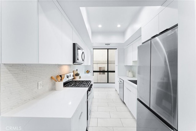 kitchen featuring backsplash, white cabinets, stainless steel appliances, and light tile patterned flooring