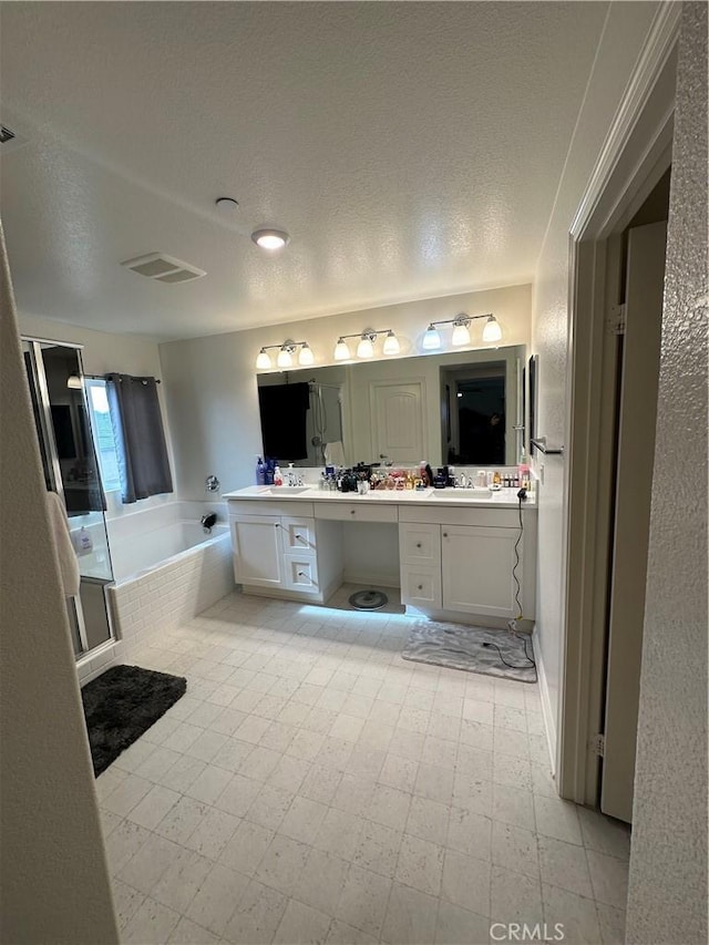 bathroom featuring a tub, a textured ceiling, and vanity