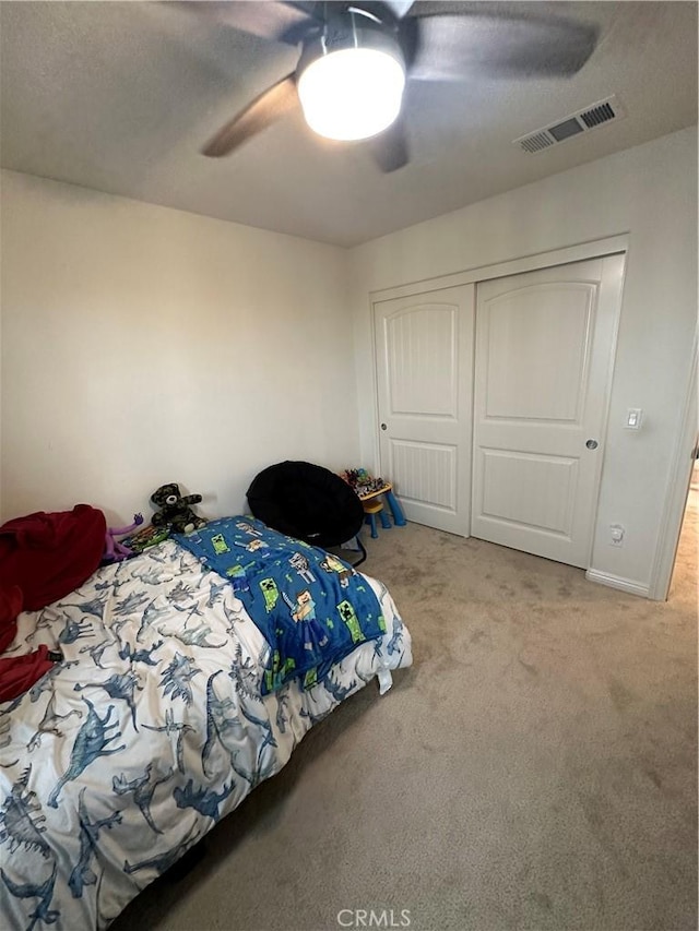 bedroom featuring light carpet, ceiling fan, and a closet