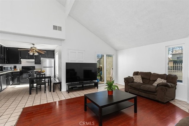 tiled living room featuring ceiling fan and high vaulted ceiling