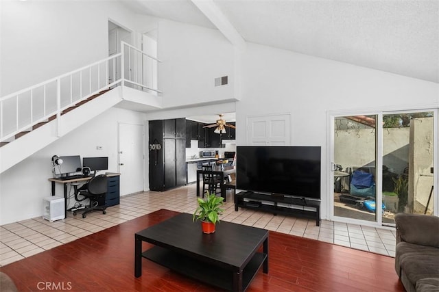 tiled living room with ceiling fan and a high ceiling