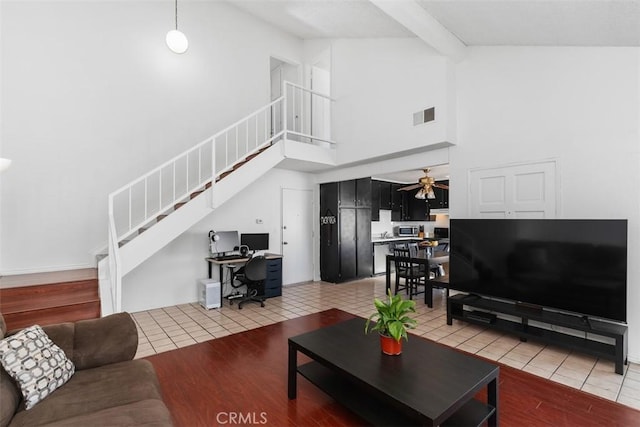 tiled living room with ceiling fan, high vaulted ceiling, and beam ceiling