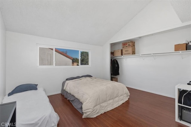 bedroom featuring dark wood-type flooring, a closet, and lofted ceiling