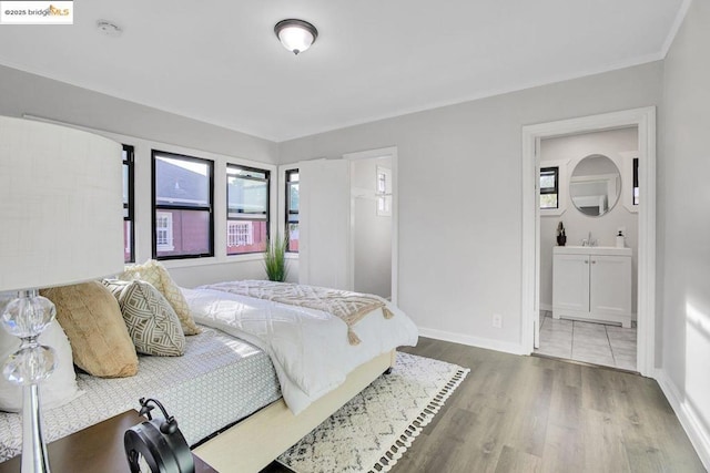 bedroom with sink, multiple windows, ensuite bath, and hardwood / wood-style floors