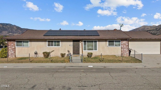 single story home with solar panels, a garage, and a mountain view