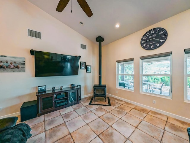 living room featuring light tile patterned flooring, ceiling fan, lofted ceiling, and a wood stove