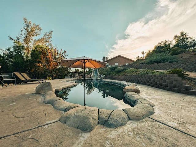 pool at dusk with a patio area