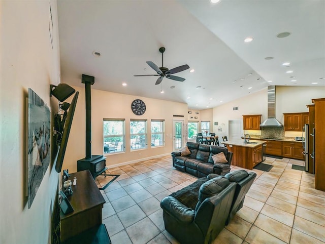 tiled living room with high vaulted ceiling, sink, a wood stove, and ceiling fan