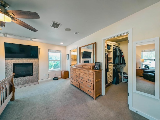 carpeted bedroom featuring a walk in closet, a closet, ceiling fan, and ensuite bathroom