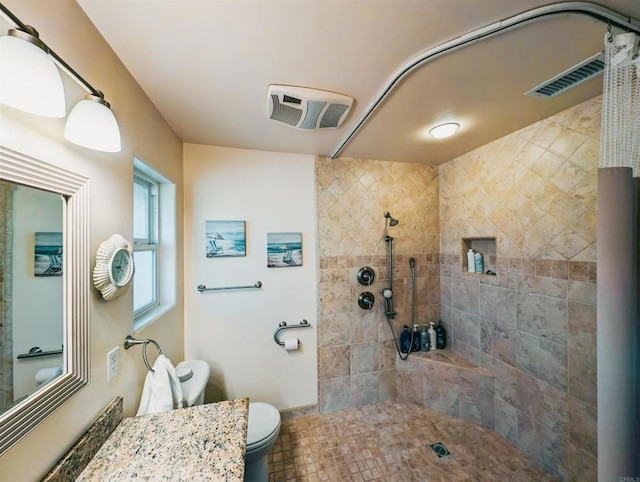 bathroom with a tile shower, vanity, and toilet