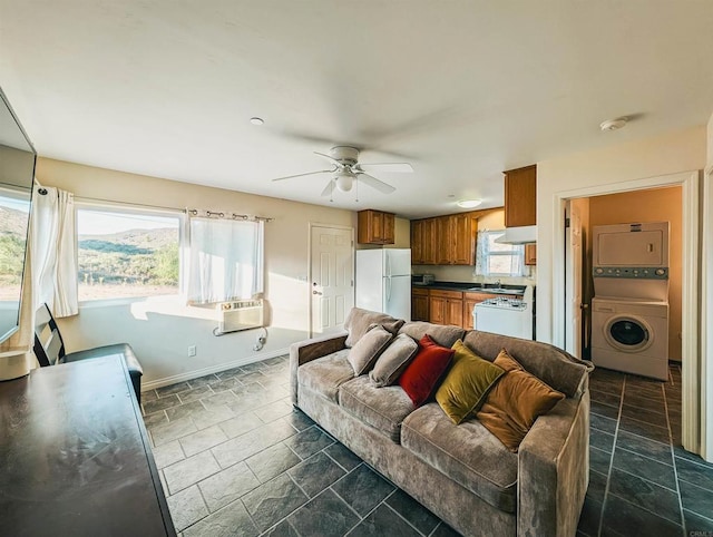 living room with stacked washer / drying machine and ceiling fan