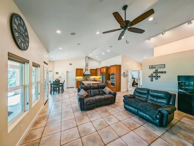 living room with vaulted ceiling, rail lighting, ceiling fan, and light tile patterned flooring