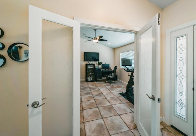 foyer featuring ceiling fan, lofted ceiling, and light tile patterned floors