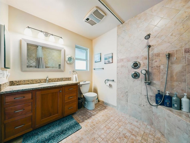 bathroom with tile patterned floors, vanity, toilet, and a tile shower