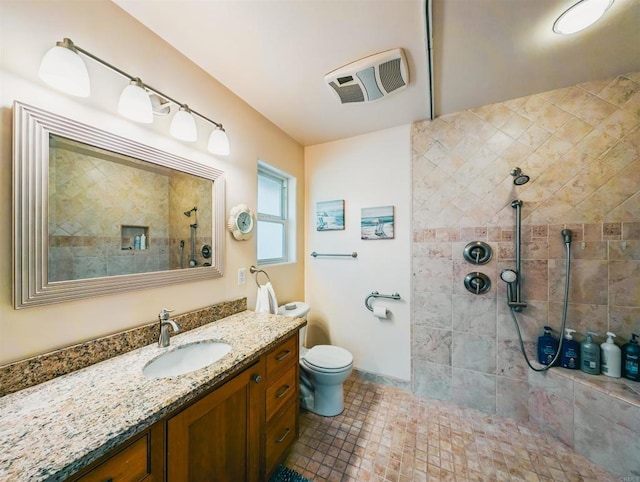 bathroom with vanity, toilet, and a tile shower