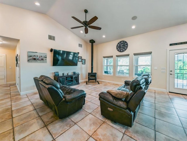 tiled living room with ceiling fan, a wood stove, and high vaulted ceiling