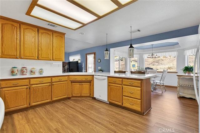 kitchen with visible vents, brown cabinetry, a peninsula, white dishwasher, and light countertops