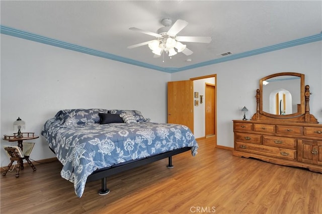 bedroom featuring a ceiling fan, light wood-style flooring, visible vents, and crown molding