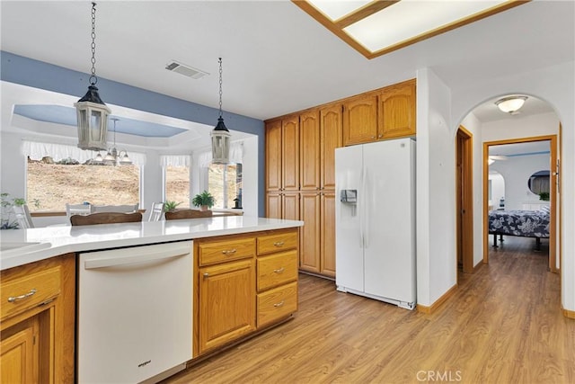 kitchen with arched walkways, light wood-style flooring, white appliances, visible vents, and light countertops