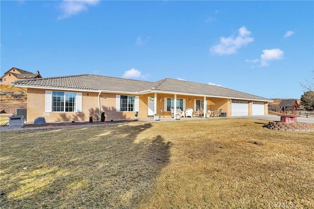 view of front facade with an attached garage, a front yard, a tile roof, and stucco siding