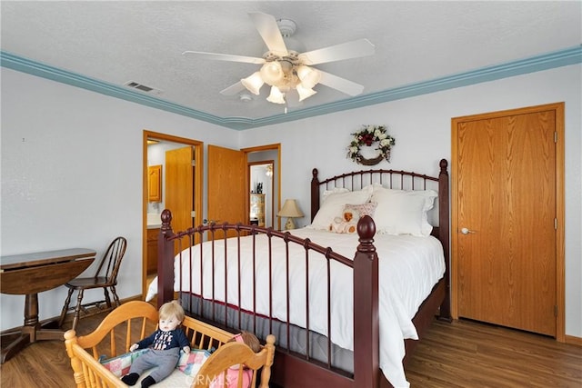 bedroom featuring visible vents, a ceiling fan, ornamental molding, wood finished floors, and a textured ceiling