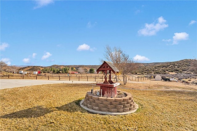 view of yard with a rural view, fence, and a mountain view