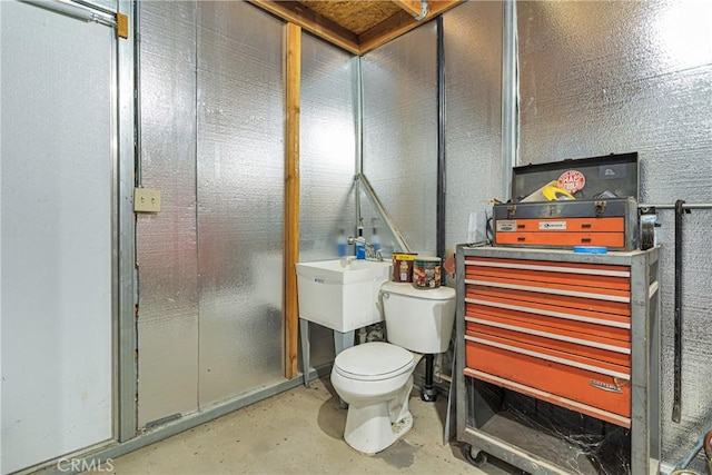 bathroom with toilet and unfinished concrete floors