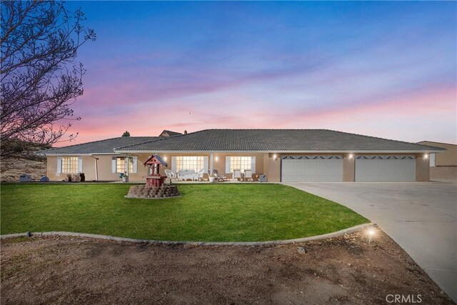 ranch-style house featuring a garage and a yard