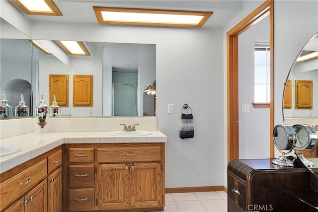 full bath with baseboards, washer / clothes dryer, tile patterned flooring, an enclosed shower, and a sink