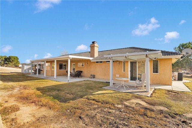 back of property featuring a patio, a chimney, stucco siding, central AC, and a tiled roof