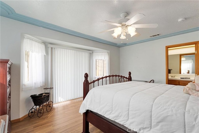 bedroom featuring visible vents, light wood-style floors, ornamental molding, connected bathroom, and ceiling fan