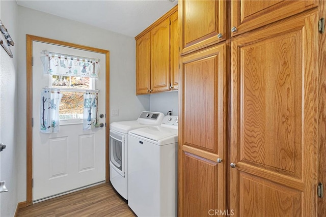 laundry area featuring light wood-style flooring, cabinet space, and washer and clothes dryer