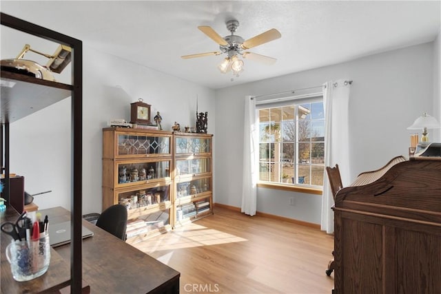 office space with light wood-style flooring, baseboards, and ceiling fan