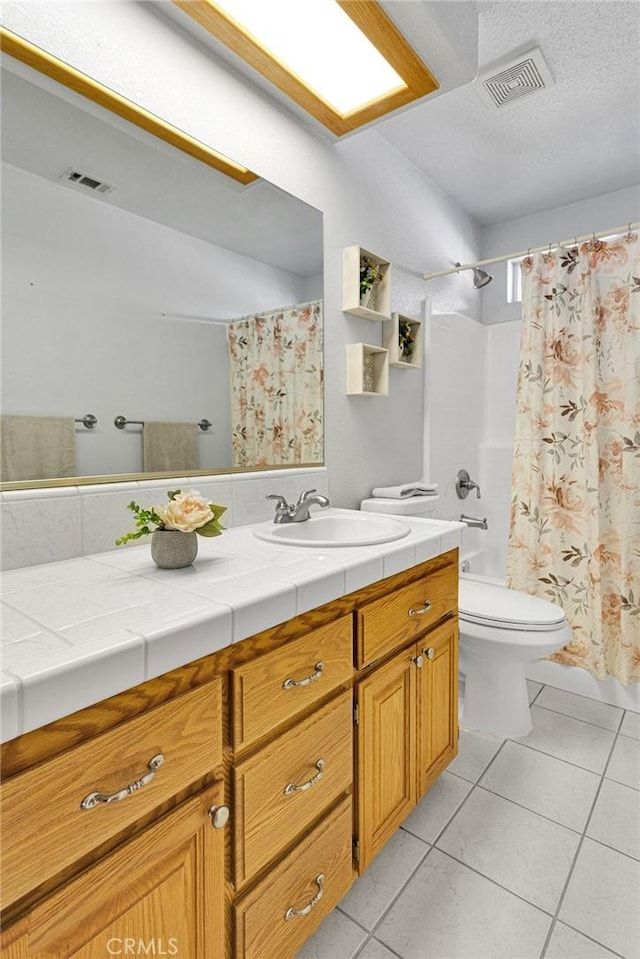 full bathroom with toilet, vanity, visible vents, and tile patterned floors