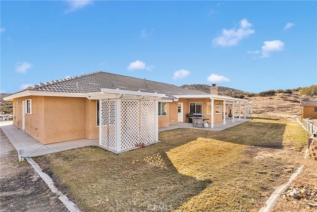 rear view of property featuring stucco siding, a patio, a tiled roof, and a pergola